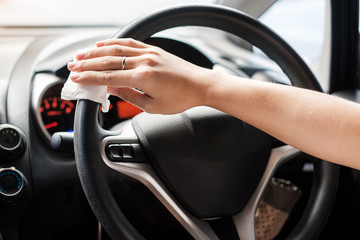 woman hand cleaning on steering wheel in his car, against Novel coronavirus or Corona Virus Disease (Covid-19). Antiseptic, Hygiene and Healthcare concept