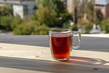 A cup of tea on a wooden table in front of a window