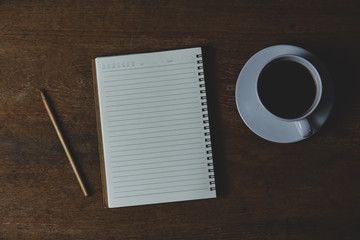 Notebook with coffee and pencil on wood table for writing at home. Work at home concept.