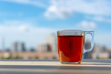 A cup of tea on a wooden table in front of a window