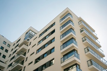 Fototapeta premium Exterior of new apartment buildings on a blue cloudy sky background. No people. Real estate business concept.
