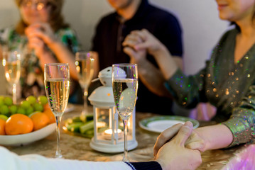 concept of holidays and celebrations-family holding hands and praying before Christmas dinner at home