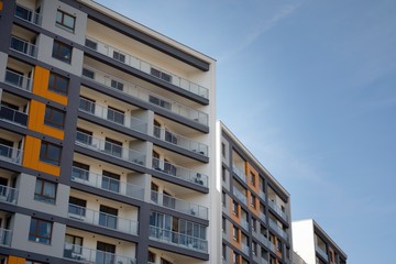 Obraz premium Exterior of new apartment buildings on a blue cloudy sky background. No people. Real estate business concept.