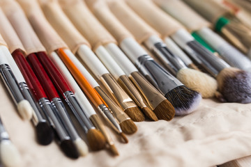 Fototapeta premium Makeup, beauty and cosmetics concept - Set of make-up brushes in a light case.