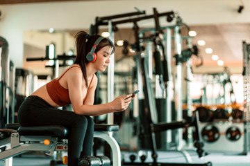 Fototapeta premium A girl wear ear phone and using smartphone in fitness gym.