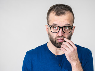 Adult clever guy wearing eyeglasses and blue shirt having thinking, focused face expression. Man focusing on his work, contemplating idea.