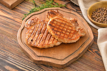 Board with cooked pork steaks on table