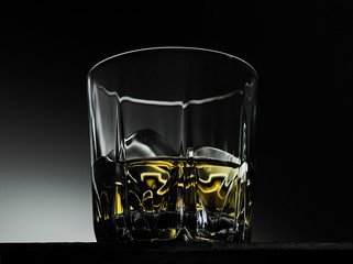 a glass of whiskey with ice on a dark background