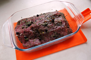 Beef and beef meat in a glass plate. Raw roast beef in spices. Cooking meat marinating in spices and herbs