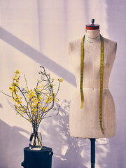 tailor's mannequin in the workshop on a bright background with flowers