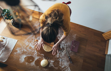 Baking homemade bread. High angle view of woman kneading bread dough on kitchen table