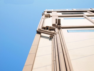 Gray drain pipe on the building's wall in the view below. Gutters and ventilation pipes are installed on the building walls on a blue sky background with copy space. Selective focus