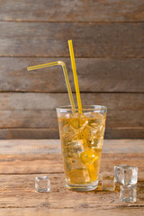 Glass of tasty cold ice tea on wooden background