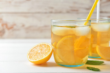Glasses of tasty cold ice tea on white wooden background