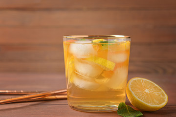 Glass of tasty cold ice tea on wooden background