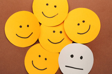 One neutral face among happy ones on color background. Concept of depression