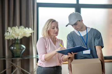 Blonde woman in a pink blouse meeting the delivery courrier