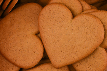  Heart shaped gingerbread cookie close-up. Delicious baked cookies with cinnamon and sugar on a ginger cookies macro background. Christmas spirit.