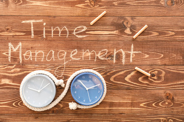 Clocks with text TIME MANAGEMENT on wooden background