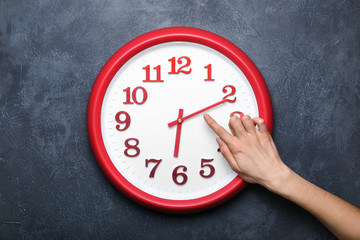 Female hand with clock on dark background. Time management concept