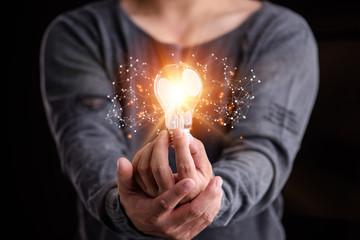 Hand of man holding illuminated light bulb, idea, innovation and inspiration concept.concept...