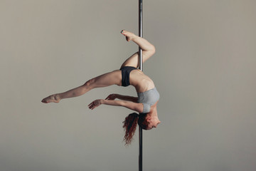 Beautiful sports girl doing acrobatics on a pole