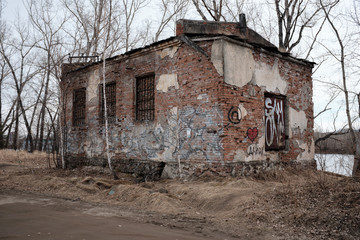 Abandoned brick building by the river. Graffiti and devastation.
