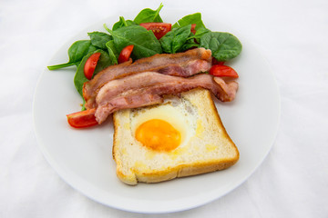 Egg in a hole bread and bacon with salad
