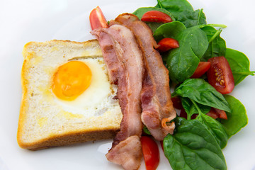 Egg in a hole bread and bacon with salad