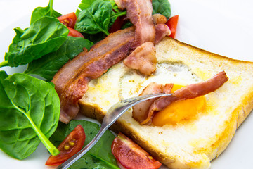 Egg in a hole bread and bacon with salad