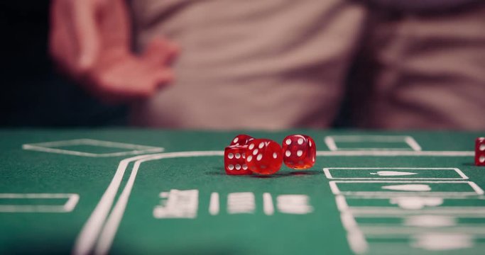 Gambler rolling the dice towards the cam on green poker table shot in 4k super slow motion