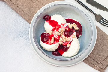 Cottage cheese pancakes with cherry sauce and nuts in grey bowl. Close up. Healthy breakfast concept.