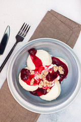 Cottage cheese pancakes with cherry sauce and nuts in grey bowl. Close up. Healthy breakfast concept.