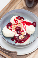 Cottage cheese pancakes with cherry sauce and nuts in grey bowl. Close up. Healthy breakfast concept.