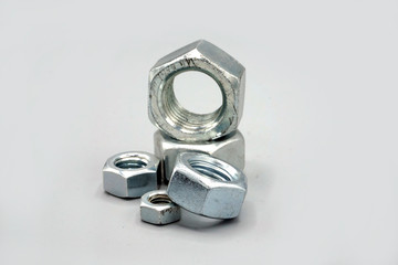 Metal screws and nuts isolated on gray background. New and shiny chrome screws and nuts. Copy space.