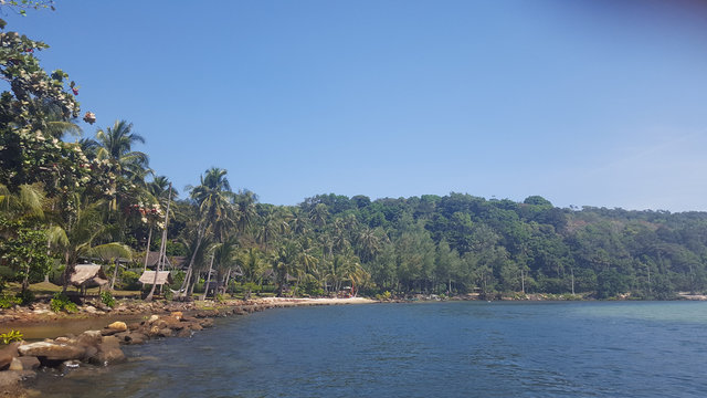 The photo was taken from a motor boat. View of the island, palm trees, ocean, spray, beach