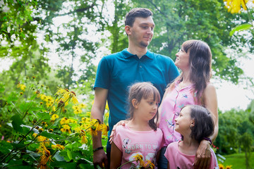 Family of four including father, mother and daughters in the Park on a summer day