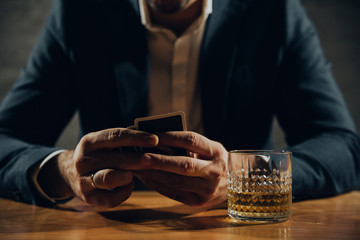 Close up of man playing card and drinking whisky.