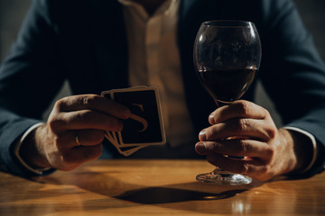 Close up of hands playing card and drinking wine.