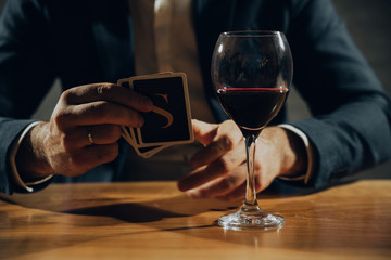 Close up of hands playing card and drinking wine.