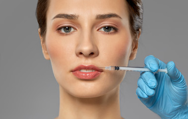 cosmetology, plastic surgery and beauty concept - beautiful young woman and hand with syringe...