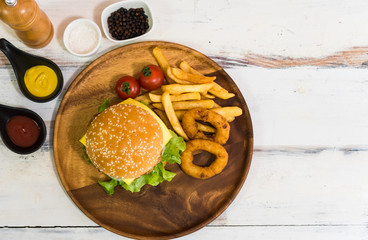 Homemade fresh tasty hamburger side dish with tomato, french fries, ketchub, mastard, salt and pepper on wood plate with white wooden plank background