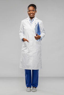 Medicine, Profession And Healthcare Concept - Smiling African American Female Doctor Or Scientist In White Coat Witch Clipboard Over Grey Background