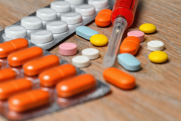 Concept of treatment options for COVID virus infection. Colorful syringes and tablets close-up.