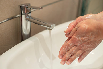 Woman washes her hands deeply under a faucet with running water. Hand washing is very important to...