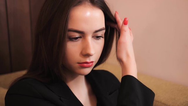 Beautiful business girl with red lips straightens her hair.