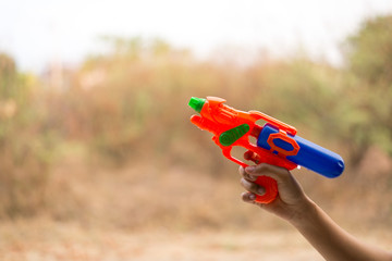 People hold water guns to play in Songkran water. Songkran New Year Festival, Thai people use water to show fun feelings. Natural orange background
