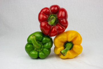 Three bell peppers, red, yellow and an orange one with white background