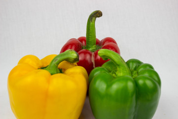 Three bell peppers, red, yellow and an orange one with white background