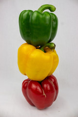 Three bell peppers, red, yellow and an orange one with white background